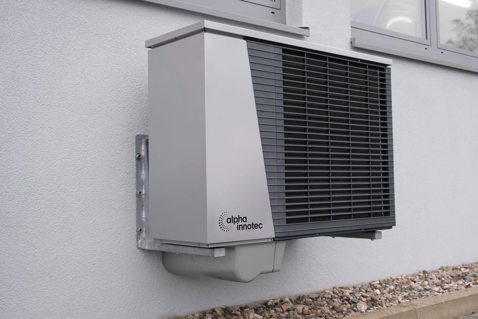 A heat pump hot water unit mounted on a rendered wall