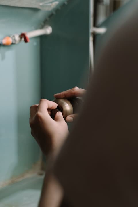 Hands adjusting a brass fitting on a pipe