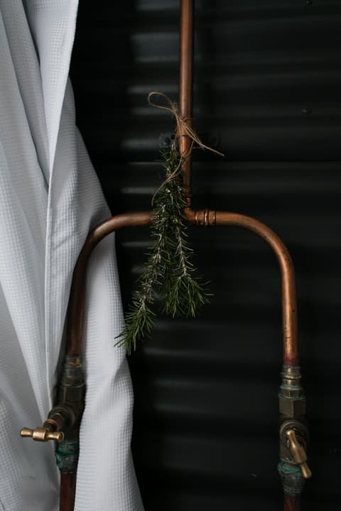 Exposed copper pipework running to a shower in a dark bathroom