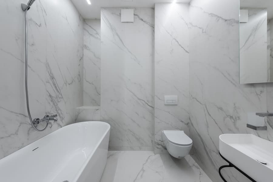A marble ensuite with a freestanding bath and wall-hung toilet