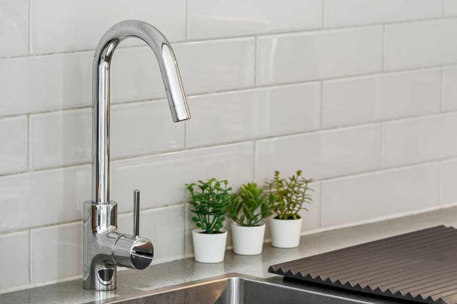 A chrome gooseneck kitchen mixer over a stainless sink