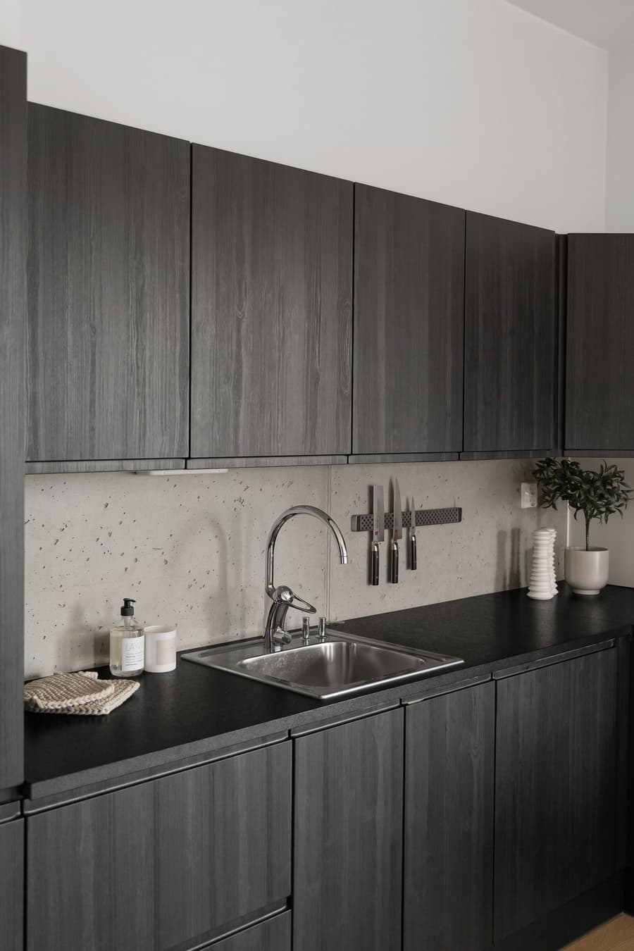 A dark timber kitchen with a stainless sink and gooseneck mixer